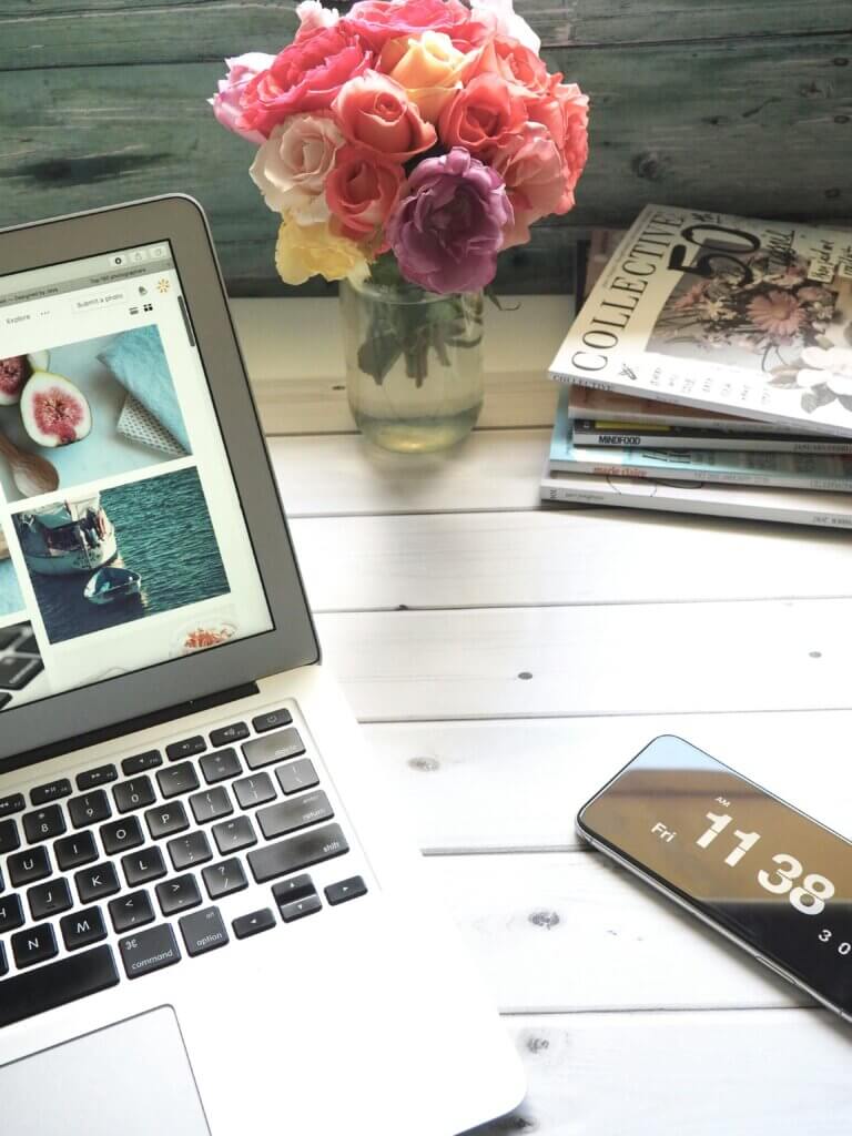 Ordinateur portable disposé sur un bureau à côté d'un bouquet de fleur et de quelques livres.