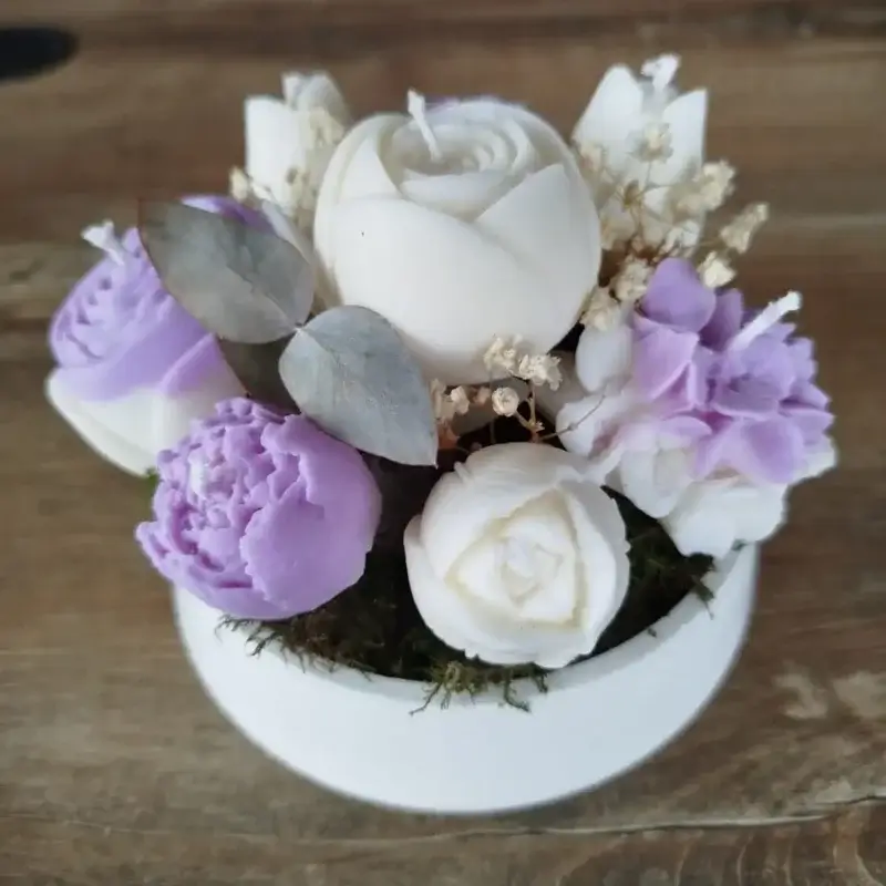 Composition de bougies en forme de fleurs de couleur parme avec des feuilles d'eucalyptus.