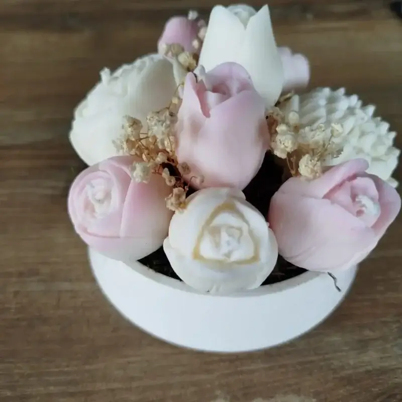 Jolie composition florale en bougies dans les tons roses disposées sur une coupelle en platre.