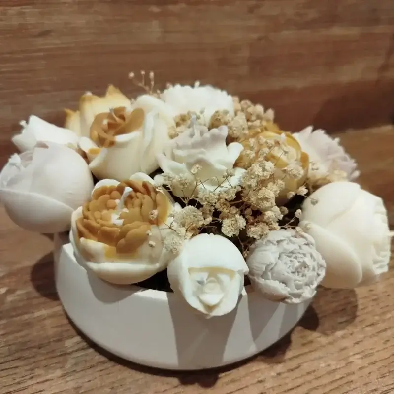 Centre de table circulaire en plâtre décoré avec des bougies en forme de fleurs de couleur outarde, beige et crème.