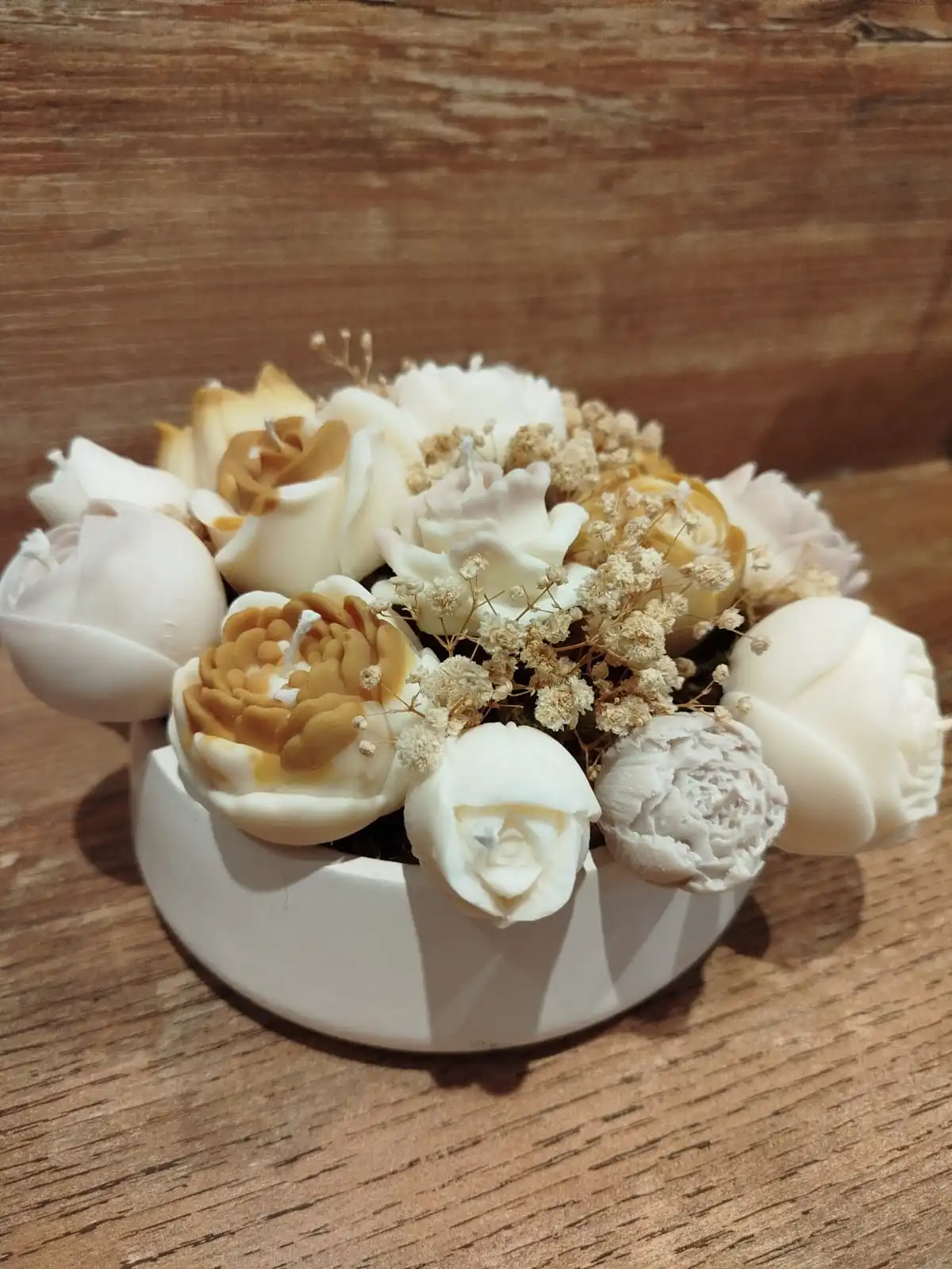 Centre de table circulaire en plâtre décoré avec des bougies en forme de fleurs de couleur outarde, beige et crème.