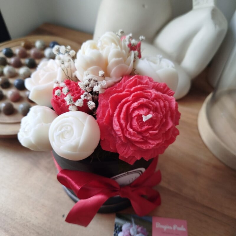 Bouquet de fleurs en bougies dans un pot noir en carton orné d'un noeud soyeux rouge..