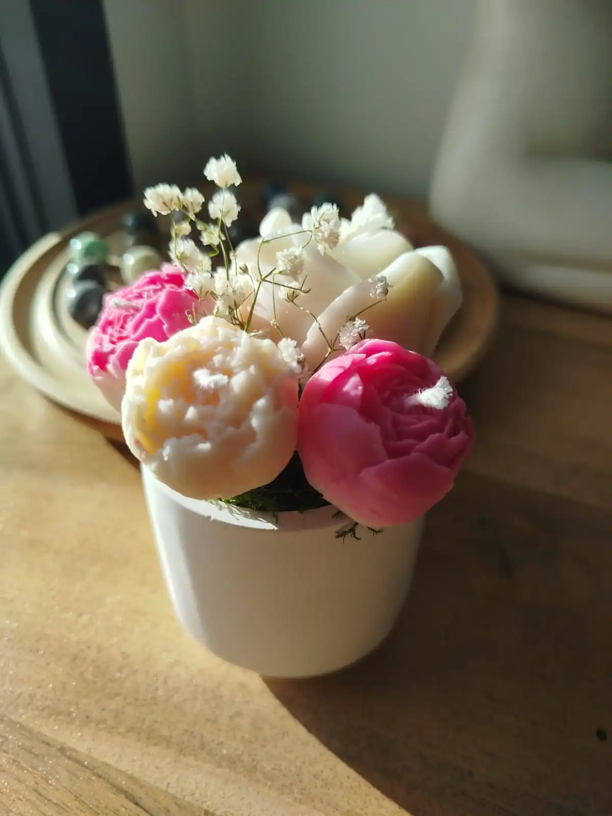 Pot en plâtre accueillant quatre bougies en forme de fleurs dont deux de couleur rose et les deux autres blanches.