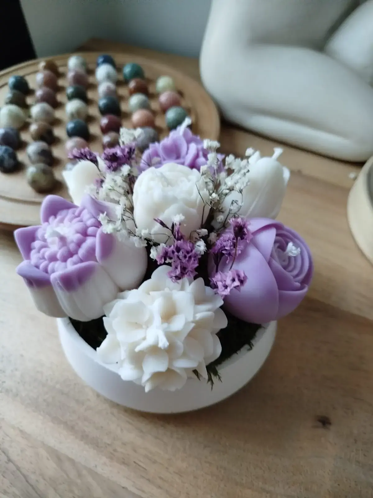 Composition de bougies en forme de fleurs dans les tons parme et blanc.