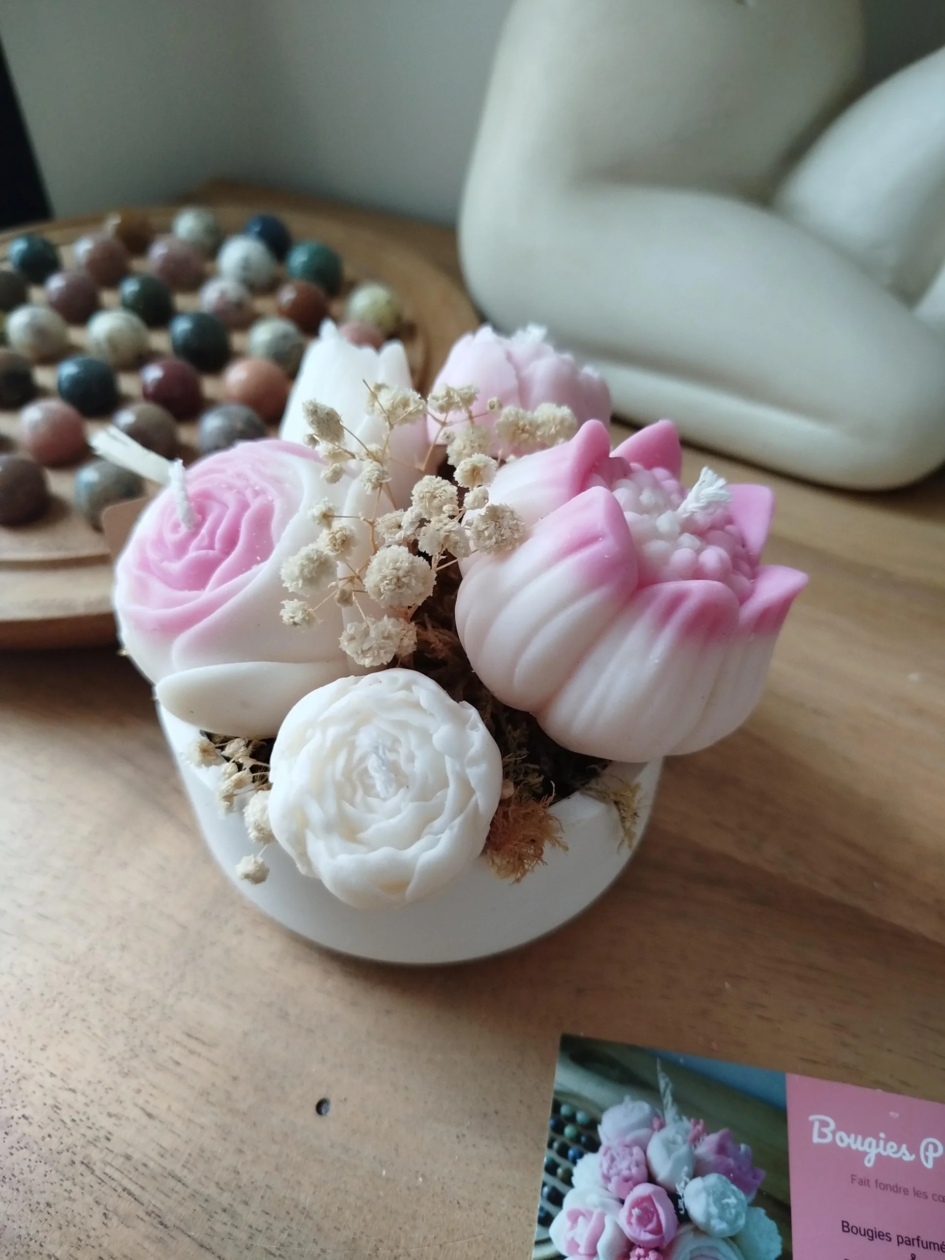 Composition florale en bougies dans une coupelle.