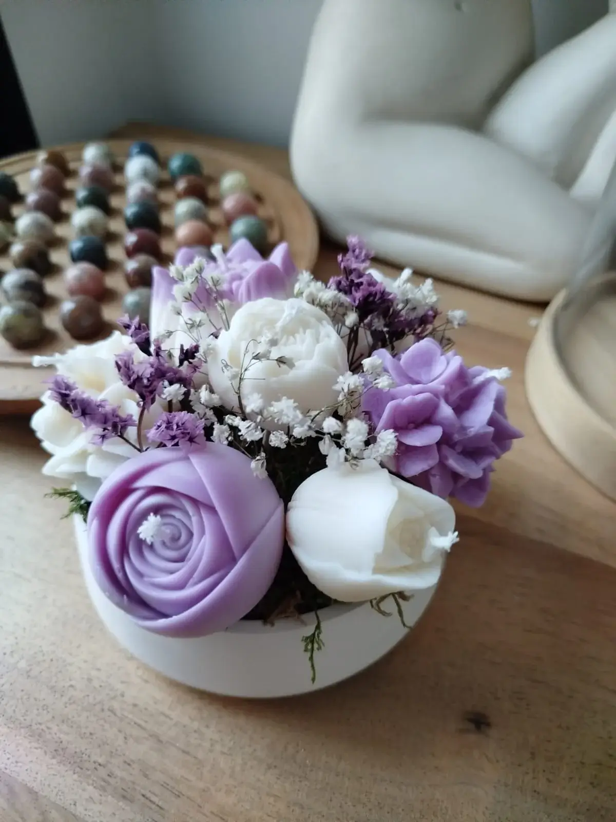 Création artisanale de bougies décoratives dans les tons parme et blanc.