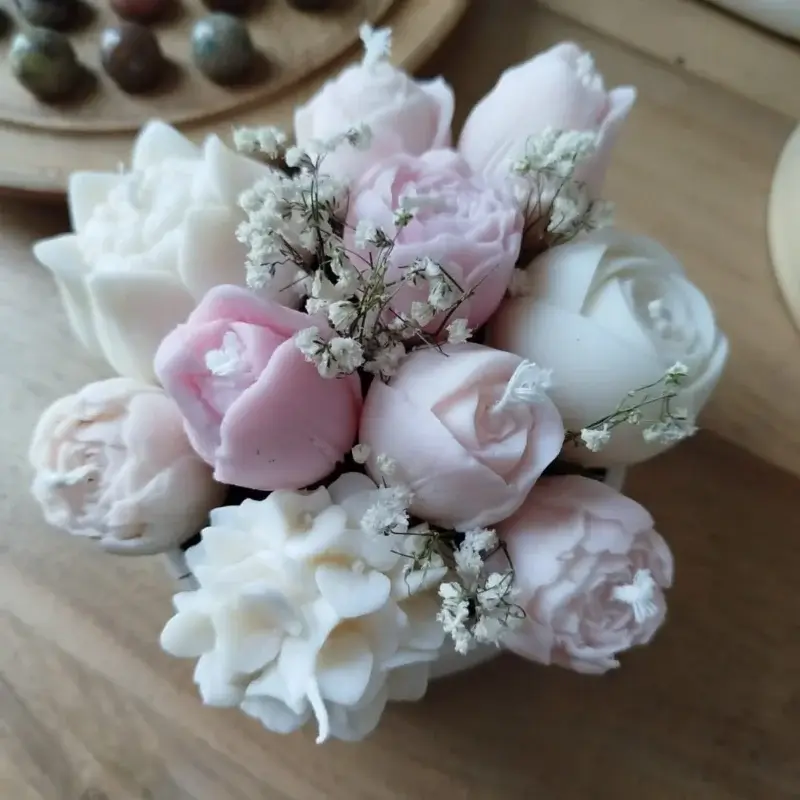 Arrangement bougies fleurs rose pâle dans coupelle en plâtre.