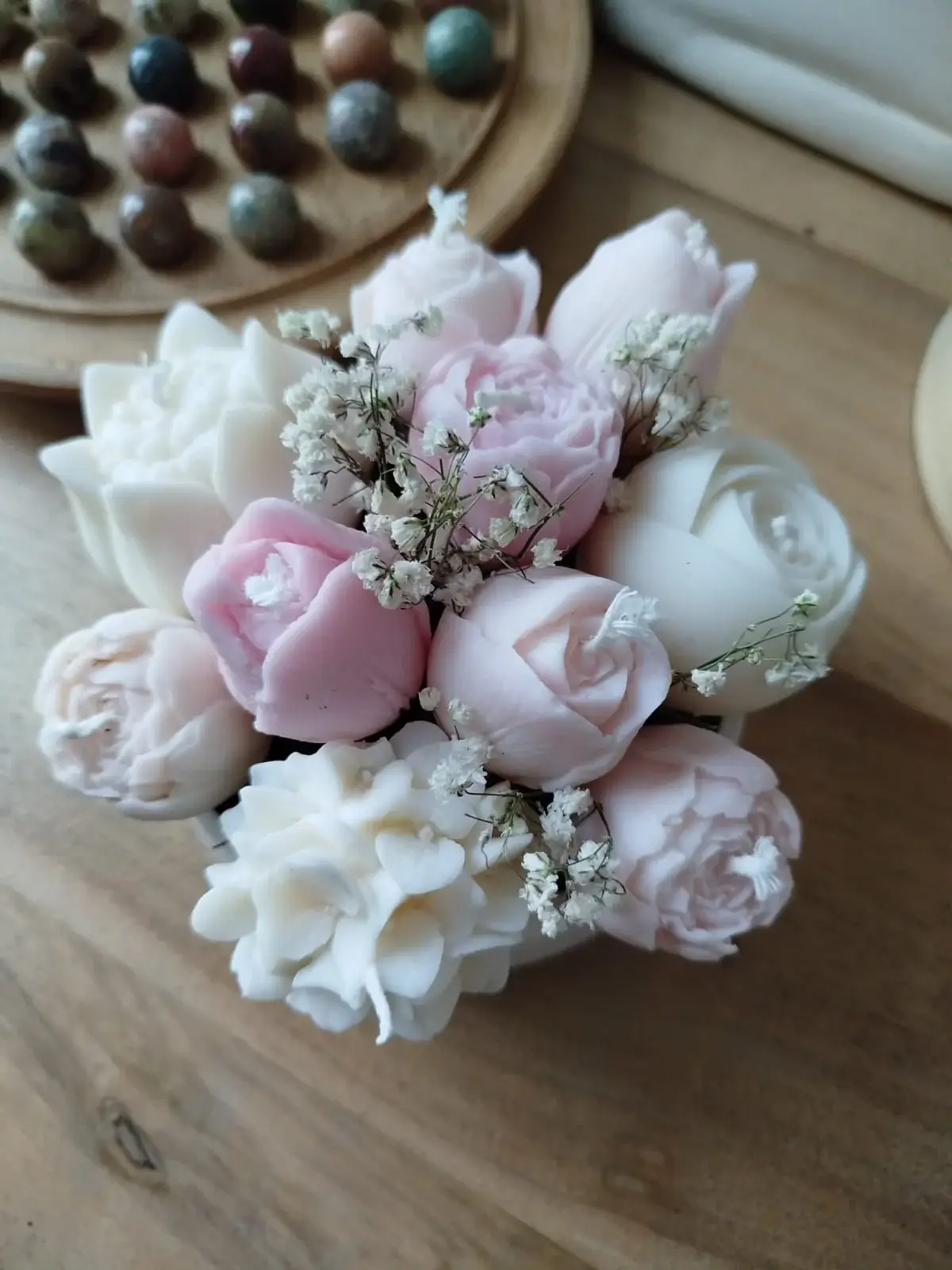 Arrangement bougies fleurs rose pâle dans coupelle en plâtre.