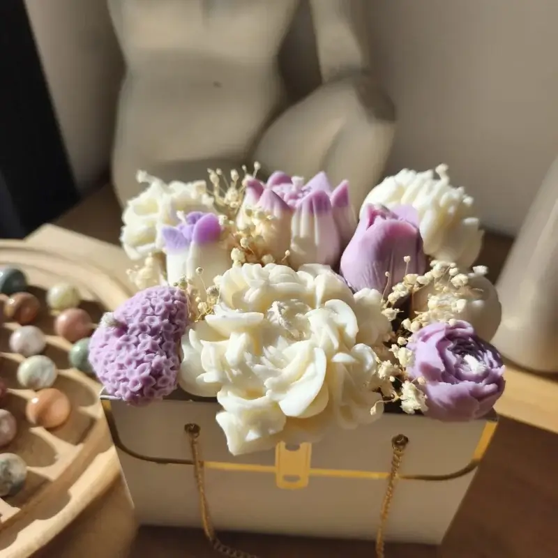Bouquet de bougies de couleur lilas et blanc dans un sac blanc cartonné.